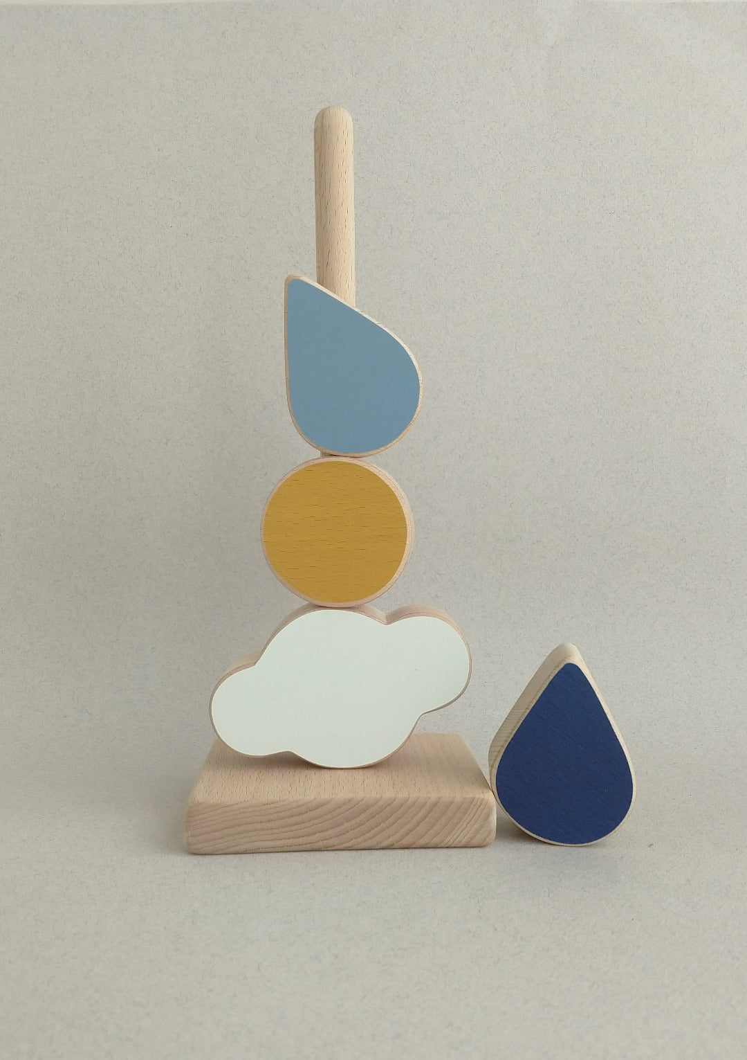 The toy combines a cloud, a sun and two blue raindrops in vivid colors with satin smooth natural wood surfaces.